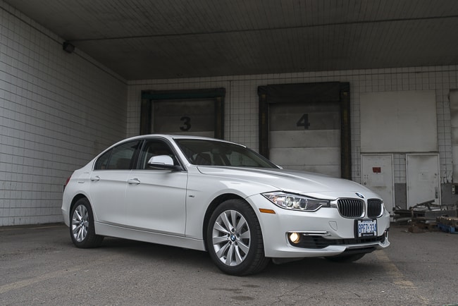 2013 BMW 328i xDrive in white parked by warehouse doors