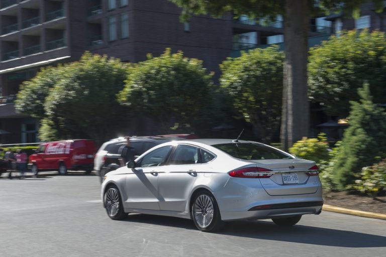 2017 Ford Fusion silver model driving on road rear view