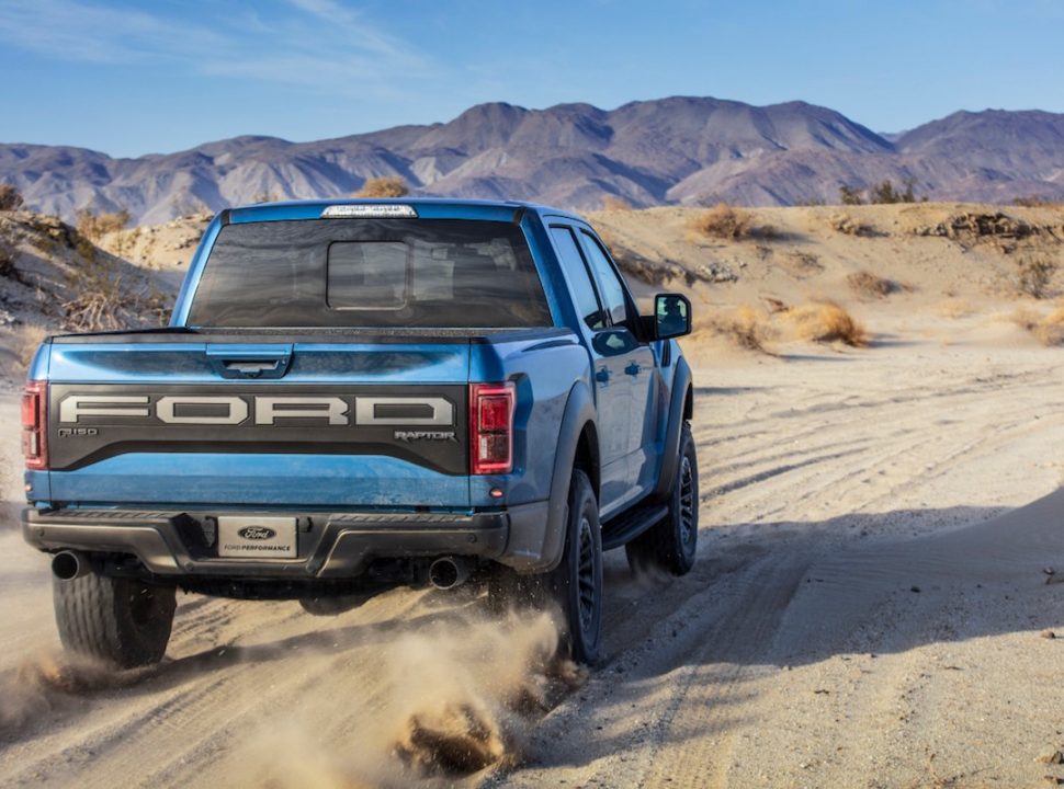 2019 Ford F-150 Raptor in blue rear shot driving in the desert