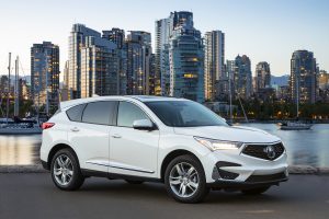 2019 Acura RDX Advance in white parked on street at sunset with buildings in the background
