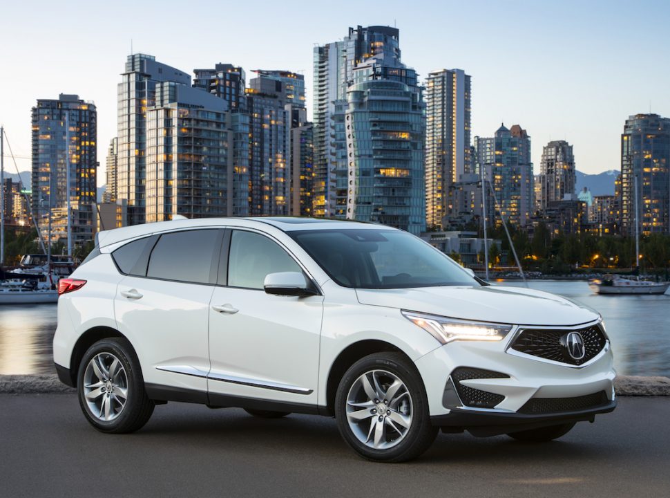 2019 Acura RDX Advance in white parked on street at sunset with buildings in the background