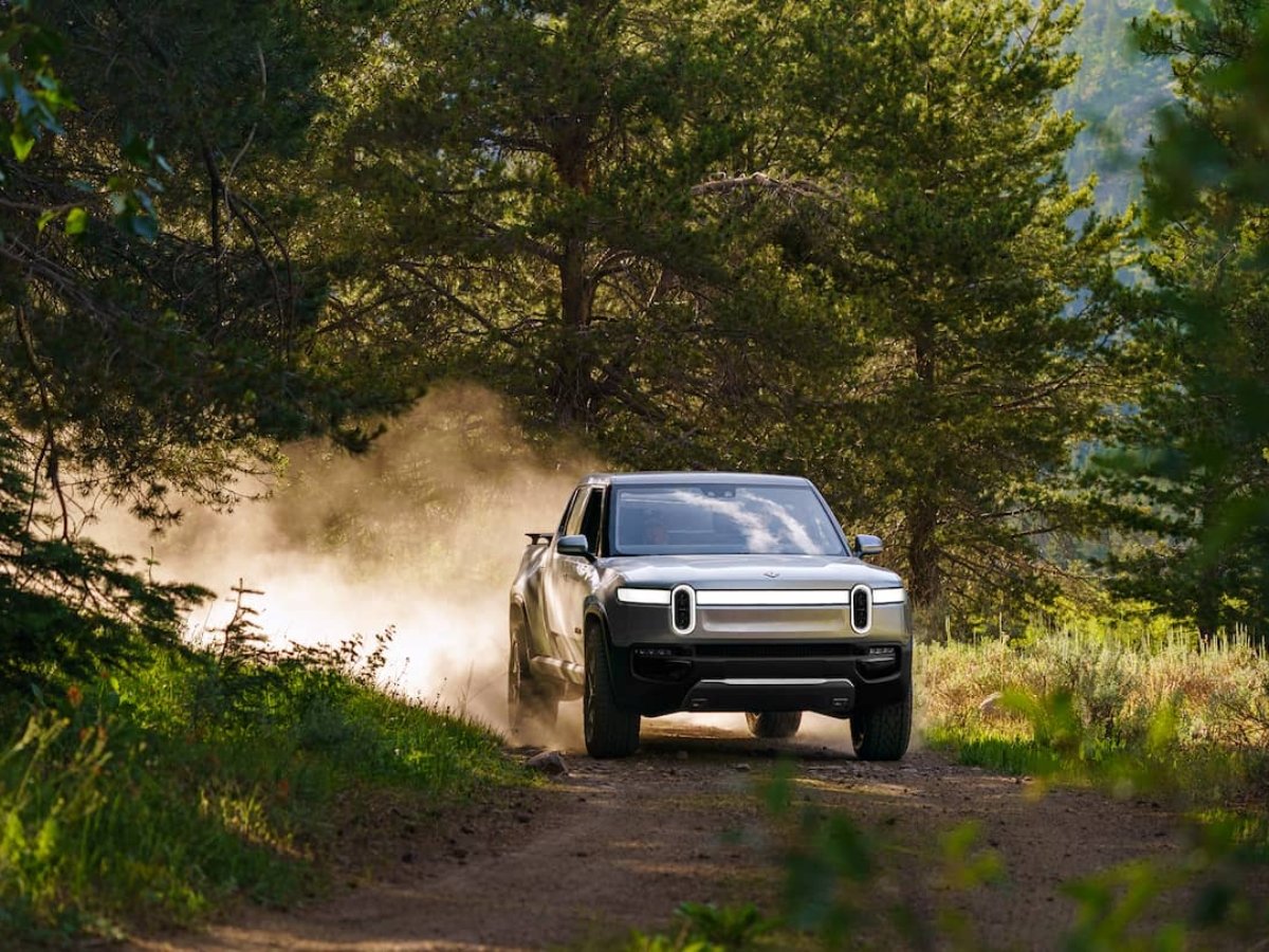 Rivian R1T Truck in silver driving through the forest