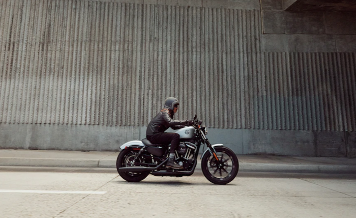 dark Harley-Davidson Iron 883 sideview on the road with rider