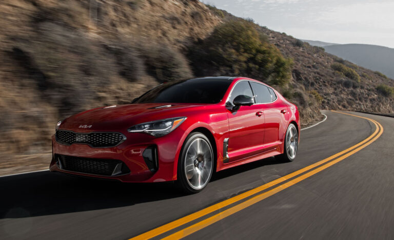 2022 Kia Stinger GT in red front view driving around a bend on the road