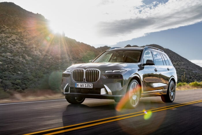 2023 BMW X7 xDrive40i driving down the road in the mountains with sun setting