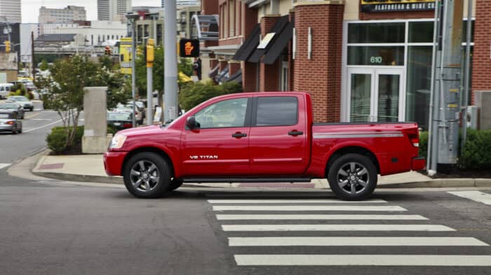 2012 Nissan Titan Crew Cab 4X4 SL in red driving on a busy city road