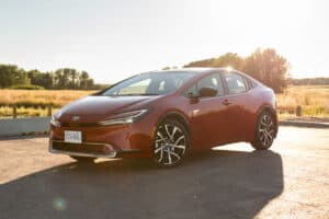 2024 Toyota Prius Prime XSE in red front profile parked on road by a field