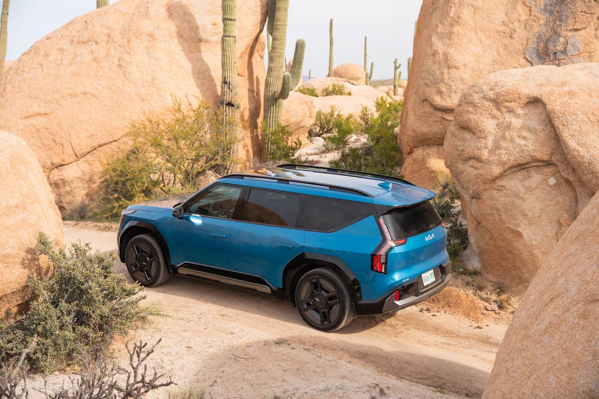 2024 Kia EV9 GT-Line rear view parked in the desert with large rocks and cactus