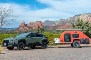 2024 Subaru Crosstrek Wilderness towing a small trailer RV parked on driveway