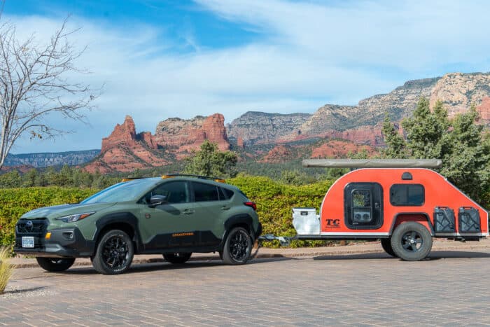 2024 Subaru Crosstrek Wilderness towing a small trailer RV parked on driveway