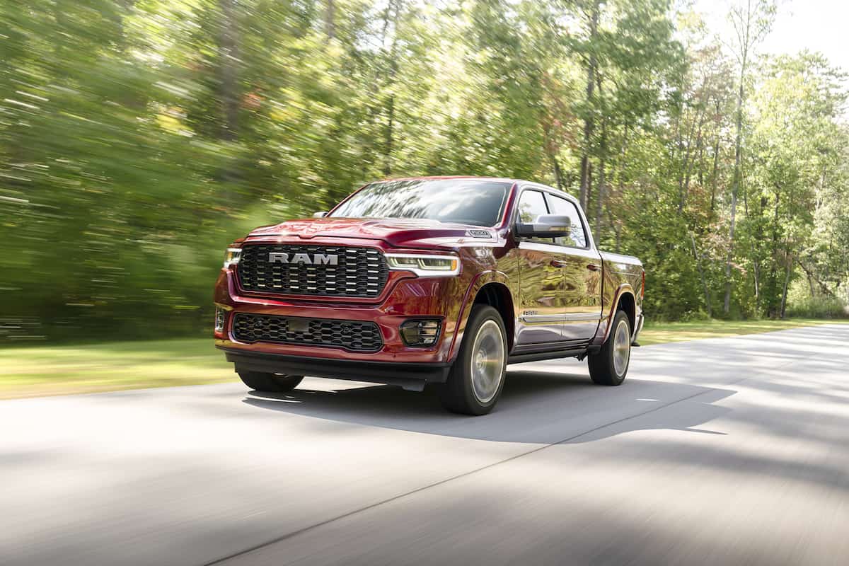 red 2025 Ram 1500 Tungsten driving on the road with trees in the back