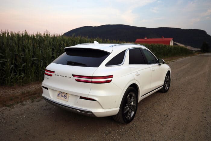 2023 Genesis Electrified GV70 Prestige AWD rear profile parked on road by red barn