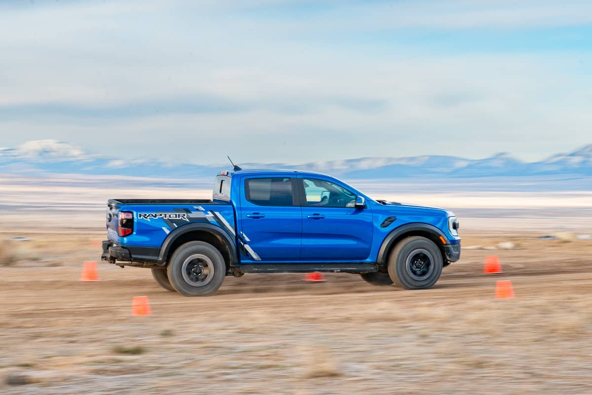 Side view driving shot of a blue 2024 Ford Ranger Raptor at the Ranger Raptor Assault School in Tooele Valley, Utah