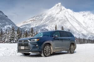 2024 Toyota Grand Highlander Platinum Hybrid MAX AWD front view parked on snowy road with mountains in the back