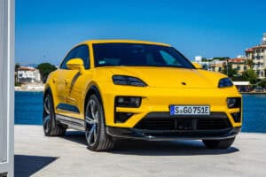 Yellow 2024 Porsche Macan EV front parked by water