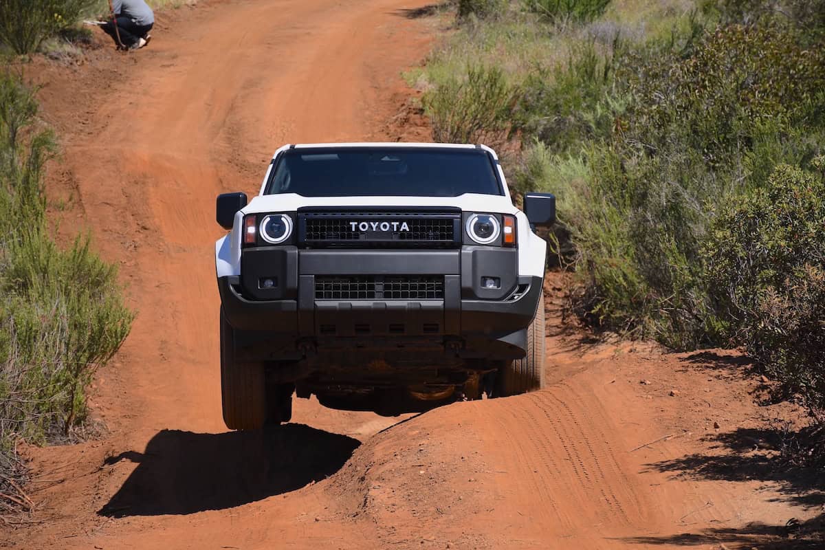 2024 Toyota Land Cruiser 1958 in white off roading driving over small dirt mounds