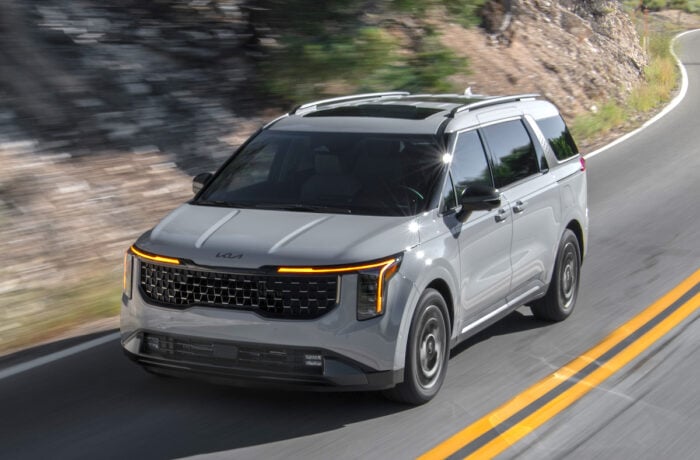 Kia SUV driving on a scenic mountain road, showcasing modern design.