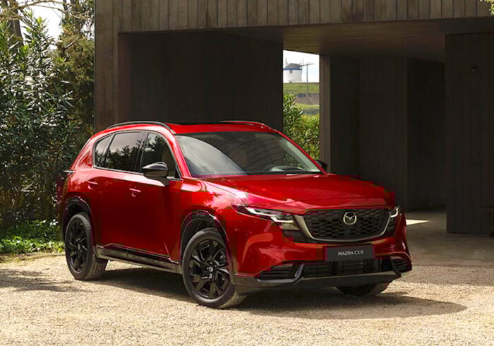 Red Mazda CX-5 compact SUV parked outside modern home, showcasing sleek design and new features.