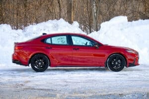 Red 2026 Toyota Camry SE Nightshade side view next to snow bank