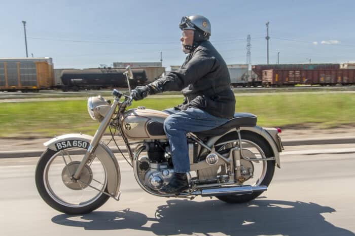 1952 BSA Golden Flash side view rolling fast on road with trains in the background