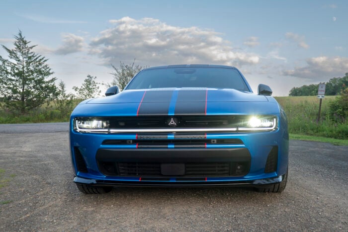 2026 Dodge Charger R/T Plus in blue with racing stripes on open road.